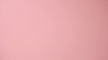 Promosyon içeriği için boş kollu, pembe stüdyo arka planında izole edilmiş, tanınmayan bir kadının dikey çekimi. Zarif avuç içlerini ürününüz için yer açarak yukarı doğru kapatın.