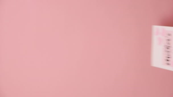 プロモーションコンテンツのコピースペースを備えたスタジオのパステルピンク色の背景壁の上に隔離された小さな心の母の日ポストカードを保持する女性の手の垂直映像 ホリデーコンセプト — ストック動画