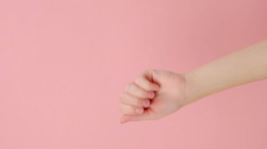 Kameraya vurulan kadın eli tıklamasının dikey videosu. Stüdyodaki pembe arka plan duvarında izole edilmiş bir poz. Reklam için fotokopi alanı var. Reklam alanı, maket. El hareketi