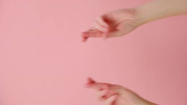Dua eden kadın ellerinin dikey videosu. İyi bir sonuç için dua ediyor. Pembe arka planda, kopyalama alanı ile izole edilmiş. Vücut dili kavramı. Reklam alanı, çalışma alanı maketi