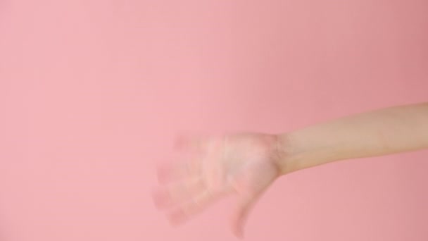 女性の手振りと挨拶の垂直ビデオは 広告のコピースペースを持つスタジオでパステルピンク色の背景の上に隔離された誰かの友人に気づきます 広告エリアワークスペースモックアップ — ストック動画