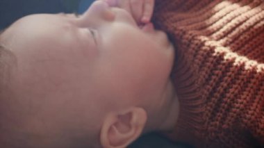 Evdeki rahat kanepede uzanan sıcak örülü süveter giymiş şirin mutlu bebek portresi. Sevimli bebek oğlan rahat bir kanepede dinleniyor. Bebeklik, sağlık ve pediatri, bebeklik konsepti