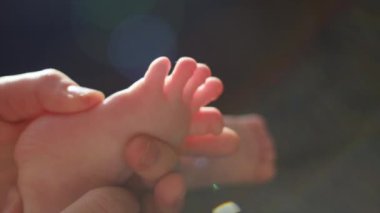 İlgili anne masajı bebek ayağı, evdeki rahat kanepe. Aile kavramı. Çocuk masajı ve doktor annenin bakımı. Ayak masajı güven ve sevgi hissi yaratır. Yavaş çekim
