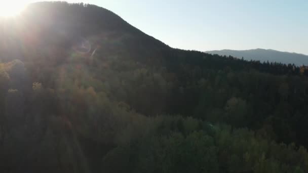 秋の山々の空中ドローン映像は 映画の素晴らしい夕日中にピークとカラフルな森林を撮影しました 夕暮れまたは夜明けの間に地平線上の暖かい日没 平和な自然と屋外キャンプのバイブ — ストック動画