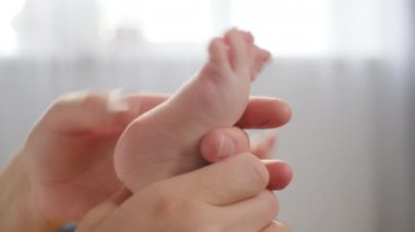 Meçhul, genç anne masajına yakın, bebek ayağı, evdeki rahat kanepe uzanıyor. Mutlu aile kavramı. Çocuk masajı ve bakım konsepti. Ayak masajı güven ve sevgi hissi yaratır.