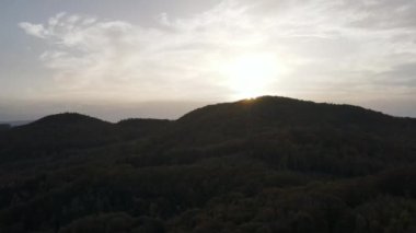 Gün batımında dağ sırasındaki sonbahar ormanının sinematik drone görüntüsü. Kimse sonbahar mevsiminde doğa düzenlemez. Sis ve bulutların arasından gün doğumu ışınları. Seyahat konsepti temiz sahne sahnesi