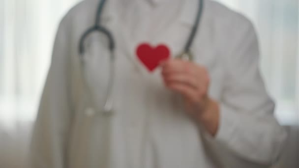 白い制服の未知の若い女性医師の近くに 病院で小さな赤い心臓の形をしたステススコープがあります ドナー 世界のハートデー 世界保健デー Csr寄付 保険コンセプト — ストック動画