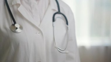Beyaz önlüklü, steteskoplu ve boş kollu tanınmayan genç bayan doktorların yakın çekimleri. Promosyon içeriği veya tasarımı için kopyalama alanı. Avuç içi, ürününüz için yer açılacak şekilde yukarı bakacak