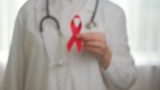 赤いリボン乳癌シンボルを保持しているプロの若い女性医師の閉鎖は 病気の人々をサポートしています チャリティー Aid Hivコンセプト — ストック動画