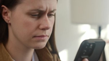 Evde cep telefonu kullanırken, gözleri ağrıyan, yorgun, beyaz bir kadını yakından çek. Üzgün kız kanepeye oturur görsel yorgunluk hisseder ve gözleri aşırı çalışma ve masajdan yorulur kuru asabiyet
