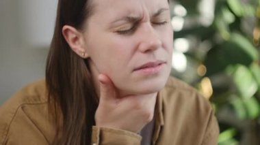 Sağlıksız, üzgün, beyaz bir kadının boğaz ağrısı çekerken elini tutması. Ağrılı boyun ve kaşları çatık, tiroid bozuklukları boğaz ağrısı, bademcik iltihabı.