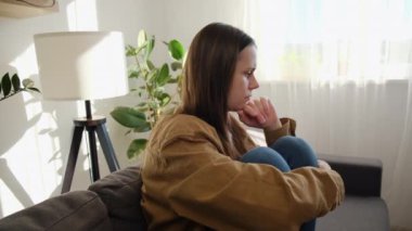 Üzgün, genç, beyaz, ilişkilerle ilgili sorunları olan, evde tek başına oturan, dizlerini kucaklayan, umutsuzluk ve endişe duyan, yalnızlık çeken, psikolojik sorunları olan bir kadın.