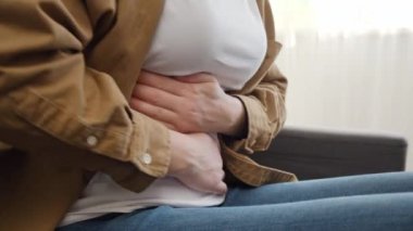 Karnı ağrıyan, karnı ağrıyan, karnı ağrıyan, karnı ağrıyan, kimliği belirsiz, genç, beyaz bir kadın. Mide iltihabı, ishal ve acı dolu dönem konsepti.