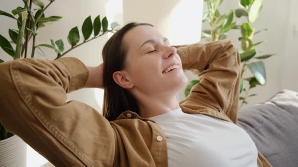 让放松的女人靠在沙发上休息呼吸新鲜空气感觉精神平衡在家里享受幸福满足的小女孩享受周末的无忧无虑的早晨舒展在沙发上 — 图库视频影像