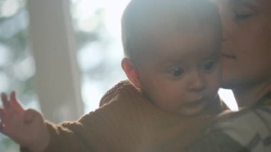 Sevgi dolu beyaz bir annenin yeni doğmuş bebeğini ellerinde tutması. Önemseyen anne kollarını tutuyor ve evdeki pencerenin yanında yeni doğmuş oğlunu okşuyor. Annelik ve çocukluk kavramı