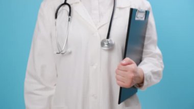 Beyaz önlüklü ve steteskoplu genç kadın doktorların elinde mavi duvarın üzerinde duran kırmızı tek bir hap var. Daha güçlü bağışıklık sistemi için takviye. Tıbbi, eczane ve sağlık hizmetleri kavramı