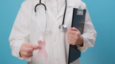 Bilinmeyen kadın doktorlara yakın. Mavi duvarda izole edilmiş insanların yaşam ve hastalıklarını desteklemek için hastanede pembe kurdele tutuyorlar. Ekim Kanser Farkındalığı Ayı. Ulusal Kanser Kurtulanlar Ayı konsepti