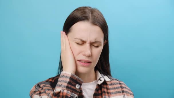 在忧郁的年轻女子耳痛和耳鸣的近视下 摆出一副蓝色的背景 耳痛的原因包括耳炎 耳垢堆积 鼻窦炎感染或气压变化 — 图库视频影像