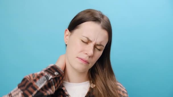 首の痛みを伴う若い白人女性の動揺の肖像画 痛みを伴う身体の部分と顔をマッサージし スタジオの青い背景の壁の上に隔離された リウマチ性疼痛コンセプト — ストック動画