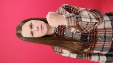 Kafkasyalı bir kadının kameraya kızgın bir şekilde el sıkışarak tehdit ettiği dikey videolar. Gömlekli bir kadın stüdyoda kırmızı arka plan duvarında tek başına duruyor. İnsanların duygu kavramı