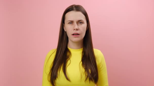 ピンクのスタジオの背景に隔離された黄色いセーターを着て 驚きでカメラを開いたショックを受けた若い女性の肖像画 アストニッシュメントコンセプト — ストック動画