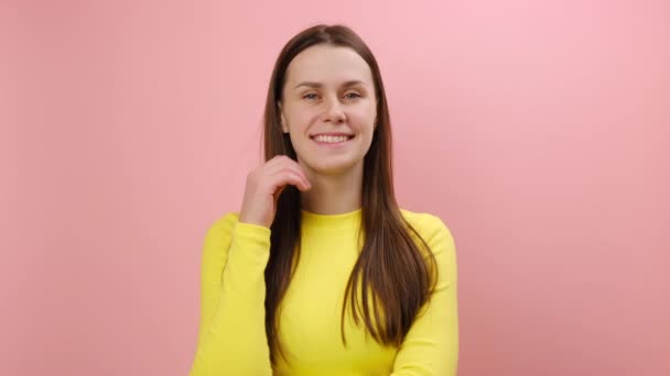 正面迷人的年轻高加索女人的画像 看着相机 调情的表情 表达快乐的情绪 穿着黄色毛衣 在工作室粉红的背景墙上摆出孤立的姿势 — 图库视频影像