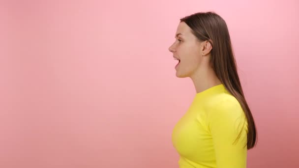 令人惊喜的是 年轻的高加索女人对这个好消息表示震惊和兴奋 穿着黄色毛衣 在工作室的粉红的背景墙上摆出孤立的姿势 哇好神奇的概念 — 图库视频影像