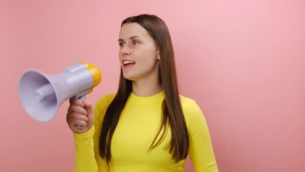 怒っている若い女性は大声でスピーカーを握って叫び 厳格な上司は叫び イエローセーターを着て スタジオのピンク色の背景の壁に隔離されたポーズを上げました 問題解決のコンセプト — ストック動画