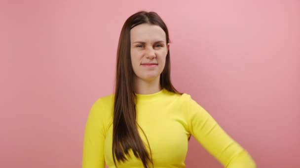 不喜欢的概念 心烦意乱的年轻女子垂头丧气 厌恶地皱着眉头 负面的反馈 穿着黄色毛衣 在工作室的粉红的背景墙上显得孤立无援 — 图库视频影像
