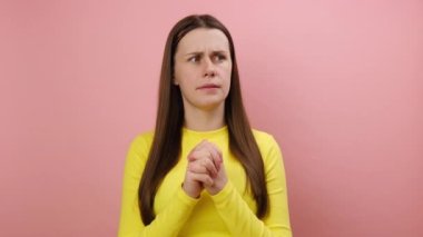 Gergin genç esmer kadının portresi rahatlamaya ve sakinleşmeye çalışıyor, nefes alıyor, yoga pozisyonunda meditasyon yapıyor sarı kazak giyiyor, stüdyodaki pembe renkli arka plan duvarına izole edilmiş poz veriyor.