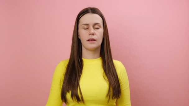 黄色い矢を指し 悲しみの表情のカメラを見て セーターを着て スタジオのピンク色の背景の壁に隔離された ダウングレードコンセプト — ストック動画