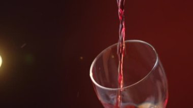 Şarap kadehini koyu arka planda kırmızı şarapla doldurup sarı ışıkla kaplayın. Ağır çekim. Kadehe kırmızı şarap dök. Kırmızı şarap camda güzel bir dalga oluşturur.