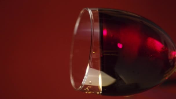 暗い背景の壁にガラスゴブレットの中の美しい赤ワイン波の垂直映像 透明なワイングラスで酒を飲みます スローモーション — ストック動画