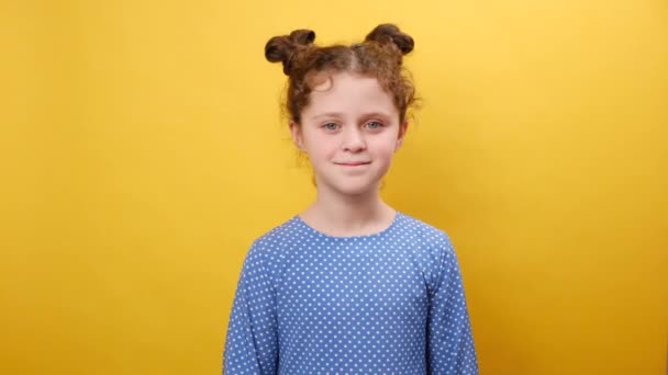 可爱而积极的小女孩展示V字的肖像 看着相机 面带微笑 在工作室里用复制空间把自己隔离在素黄的背景墙上做广告 — 图库视频影像