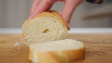 Genç bir kadın ekmeği ya da ekmeği mutfak tahtasına keser. Sabah kahvaltısı hazırlıyorum. Bruschetta ya da kanepe için dilimlenmiş Fransız ekmeğini kapat. Taze ekmek kanepesi.
