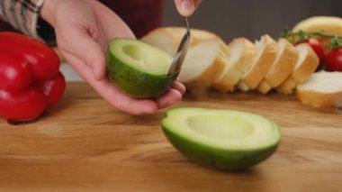 Avokado etini kaşıkla kepçelemek. Kadın şef avokado hamuru kepçesine yakın çekim. Sağlıklı gıda konsepti.