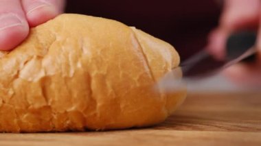 Mutfakta ekmek kesen kadınların ellerini kapatın. Sandviç yapmak için ekmek dilimliyorum. Sabah kahvaltısı hazırlıyorum. Fransız ekmeği kesiyorum.