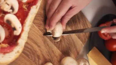 Bilinmeyen genç bir kadının dikey görüntüleri ahşap mutfak tahtasıyla şampiyon mantarlarını kesiyor. Çeşitli malzemelerle ekmek teknesi pişirme işlemi. Yavaş çekim