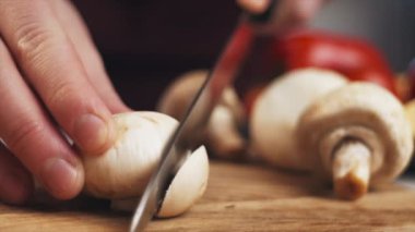 Meçhul genç bir kadının tahta keserek kraliyet şampiyonu mantarını bıçakla dilimlediği yakın plan. Çiğ organik sebzeler. Diyet sağlıklı yaşam tarzı konsepti. İlginç bir tarif. Yavaş çekim