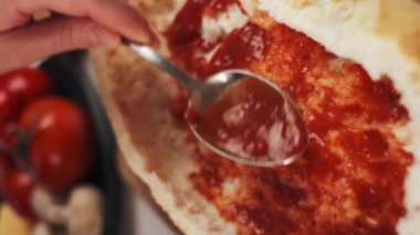 Bir kadının domates sosunu ekmek teknesine sürdüğü dikey video ev mutfağındaki tahta tahtaya, iştah açıcı vejetaryen yemek konseptine. Yavaş çekim
