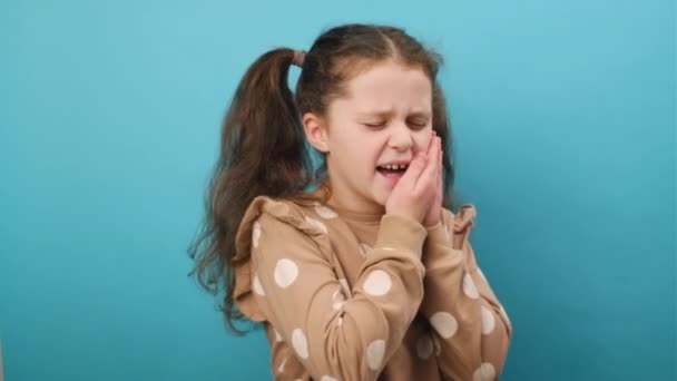 少女面颊接触的肖像 紧闭的眼睛带着可怕的表情 有疼痛的牙痛 敏感的牙齿 在蓝色的背景墙上呈孤立状 牙科问题 — 图库视频影像