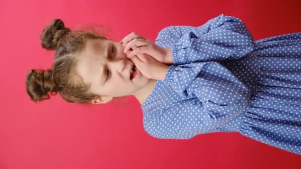 赤いスタジオの背景に隔離された痛みを伴う歯痛 敏感な歯 洞窟の表現で目を閉じる頬に触れる少女の子供の垂直映像 歯科の問題 — ストック動画