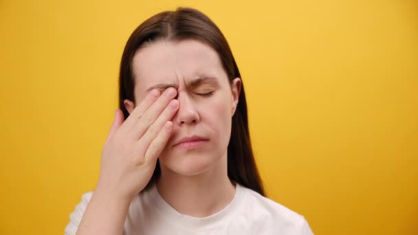 年轻女子眼部疼痛 孤立在黄色的背景墙上的特写 疼痛的原因包括隐形眼镜问题 结膜炎 干眼症或过敏 — 图库视频影像