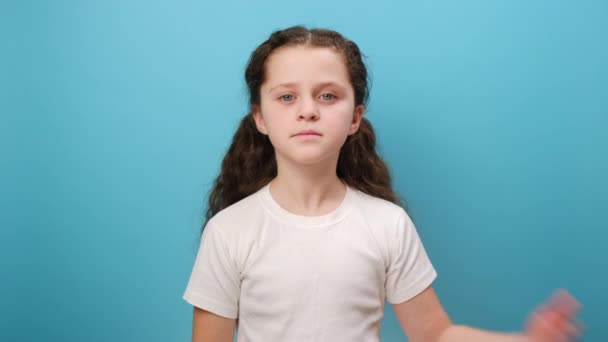 真実を語るために彼女の手のひらを上げる深刻な19歳の少女の肖像画 子供は真実を語ることを誓い スタジオの明白な青い背景の壁の上に隔離された白いTシャツを着ています — ストック動画