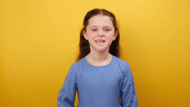 興奮するかわいい素敵な少女の子供8 9歳の肖像画は スタジオで黄色の背景の壁の上に隔離されたメガフォンの熱いニュースを叫んで青いドレスを着ています 子供時代のライフスタイルコンセプト — ストック動画