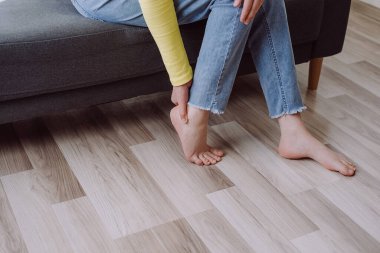 Meçhul bir genç kadın, baldır kaslarına masaj yapıyor, kramp ya da spazm geçiriyor. Baldırlarında iltihap kaynaklı travma, evde tek başına kanepede oturuyor. Kas ağrısı ya da bacak ağrısı. Sağlık hizmeti kavramı