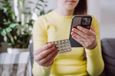 Akıllı telefonu okumak, reçete yazmak, bilgi hakkında hap etiketi metni, talimatlar, yan etkiler, eczane tıbbı konsepti için kullanan beyaz kadın seçici odağı