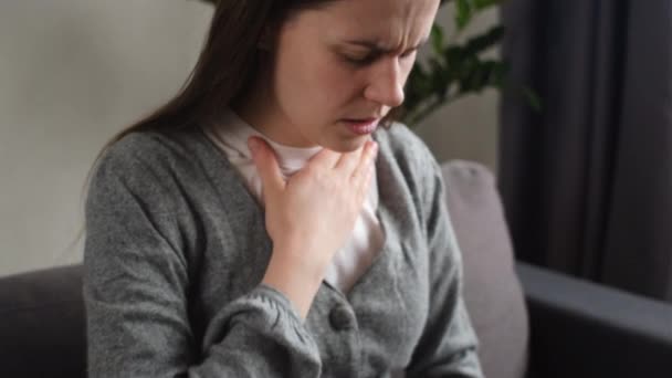心臓発作の脅威 若い慎重な女性は胸に強い痛みを感じ 自宅でソファーに座っている 病気は頻繁に発症する 医療と人々のコンセプト — ストック動画