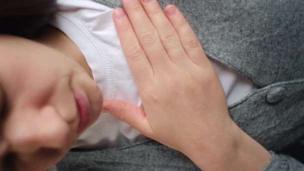 一个悲伤的年轻女子把手放在胸前的垂直镜头 让人感到不舒服 胸部疼痛 胃食管反流病有频繁的打嗝 医疗和人的概念 — 图库视频影像