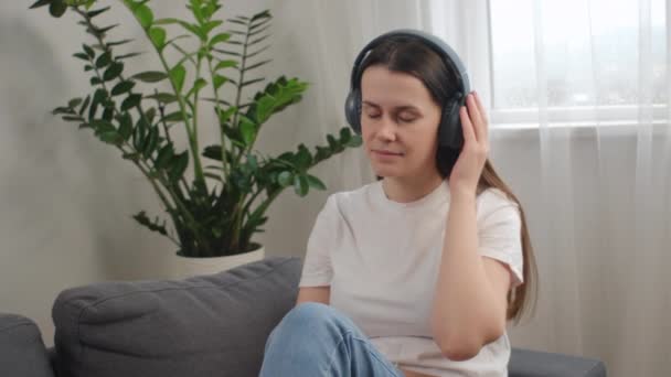 Mujer Joven Atractiva Despreocupada Sentada Cómodo Sofá Con Auriculares Disfrutan — Vídeos de Stock